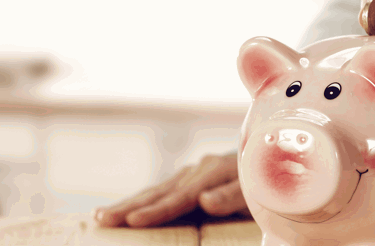 Someone putting money in a piggy bank